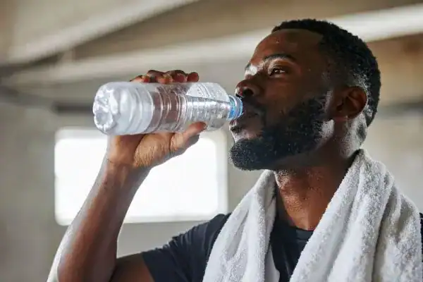 Image of man drinking water to improve hydration Lutterworth after work out.
